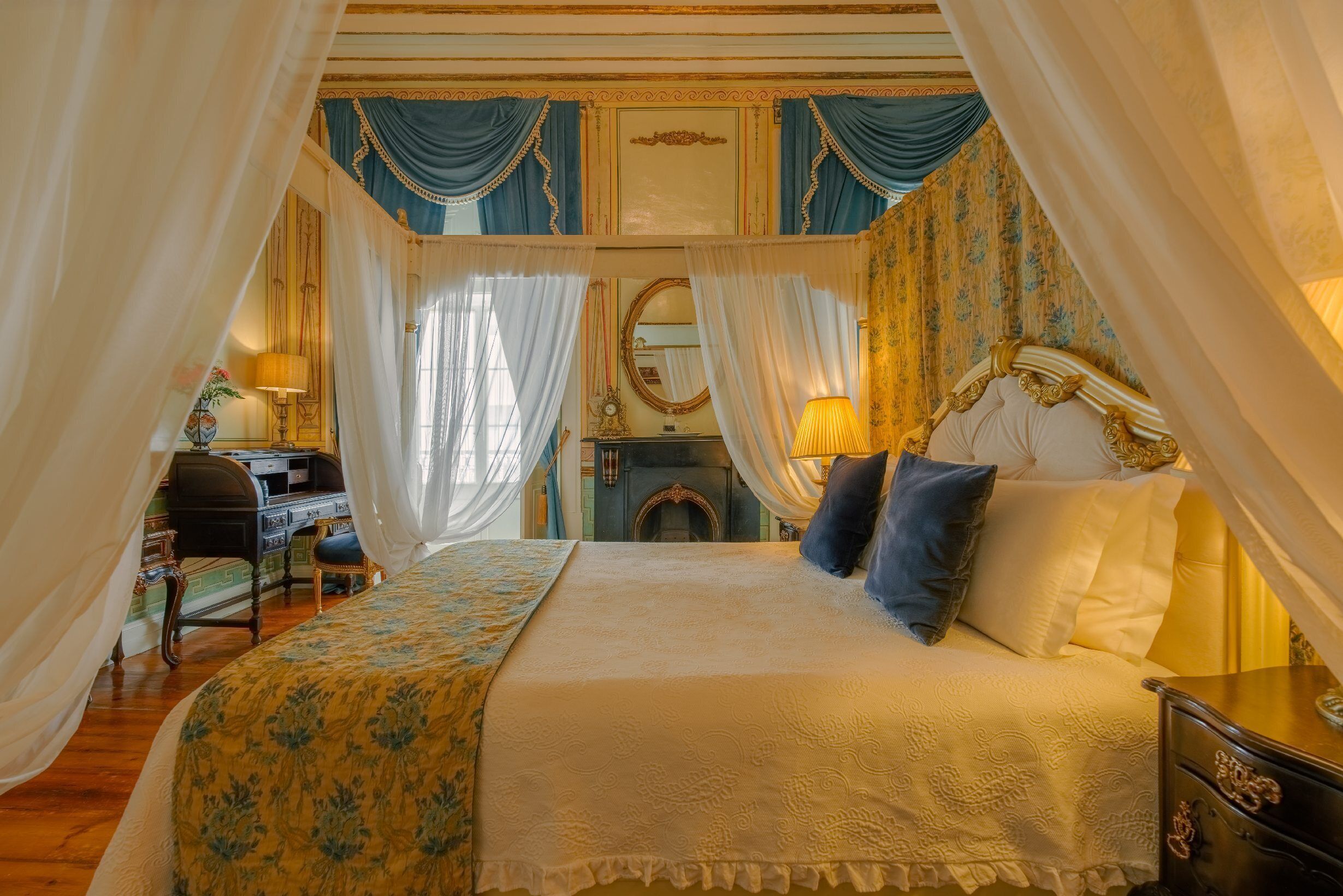 A bedroom with a large bed, a desk, and a mirror.