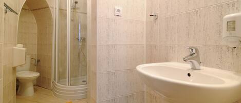 A bathroom with a shower, toilet, and sink.