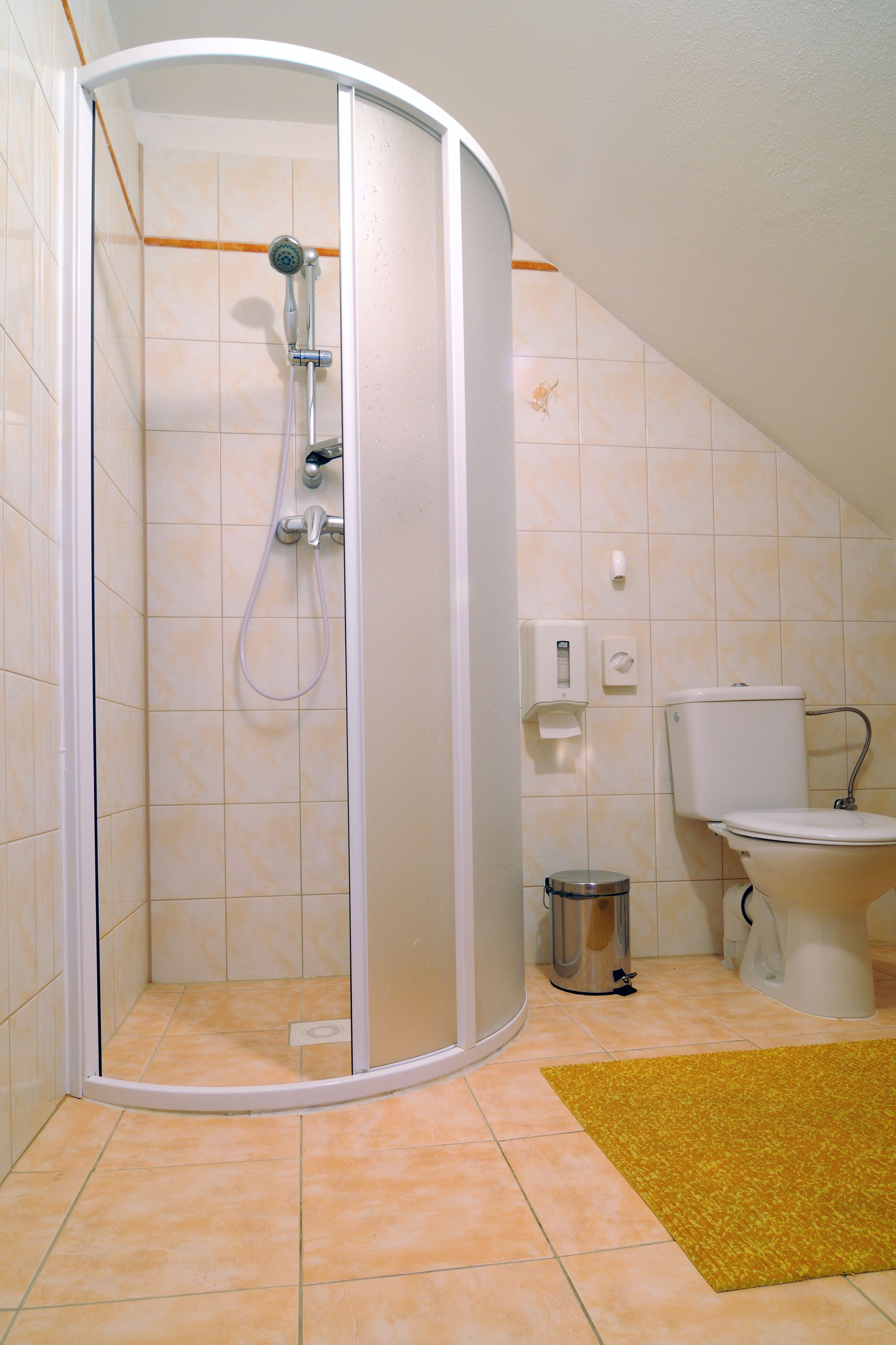 A shower with a glass door, a toilet, and a sink in a bathroom with tiled walls and floor.