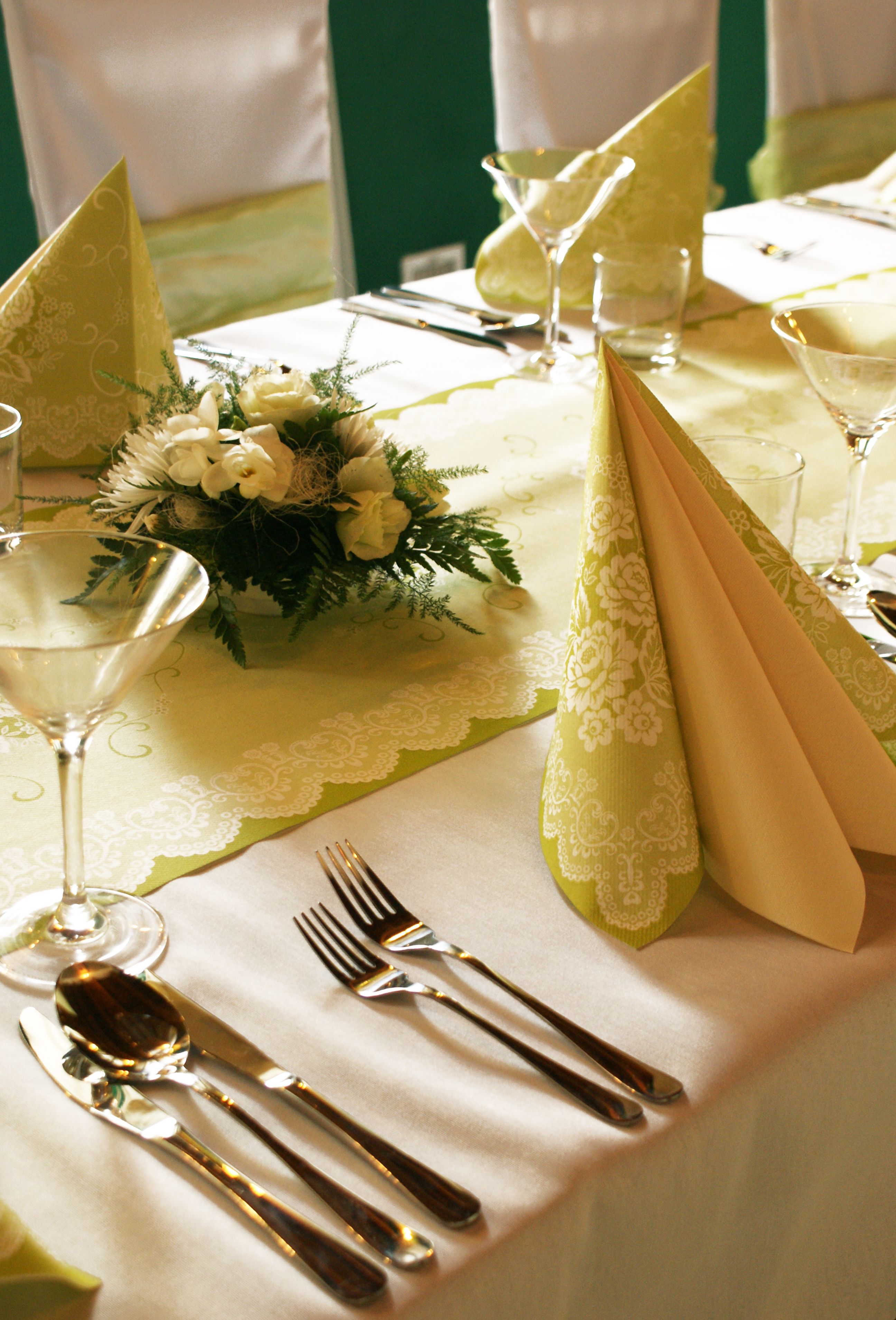 Una mesa dispuesta para una cena elegante, con cubertería fina, servilletas decorativas y un centro de mesa con flores.