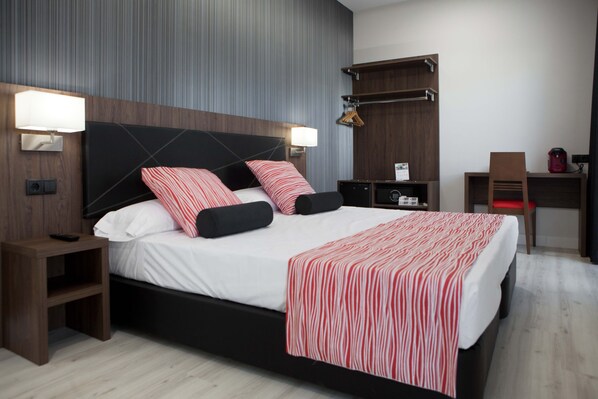 Une chambre d’hôtel moderne avec un grand lit, des tables de chevet, un bureau et une chaise.