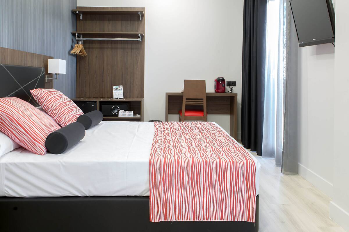 Une chambre d’hôtel moderne dotée d’un grand lit, d’un bureau, d’une télévision à écran plat et d’une fenêtre de toit.
