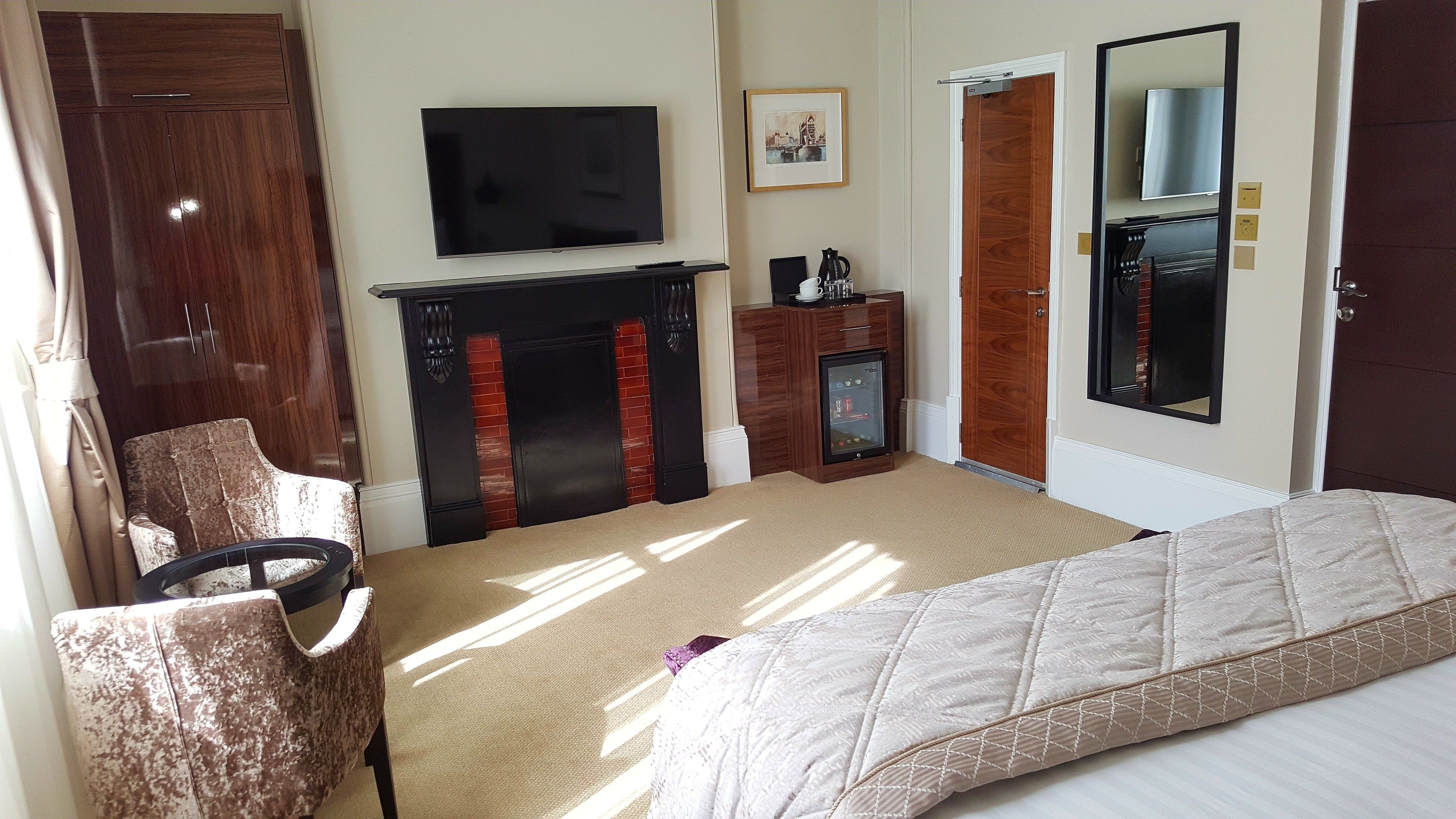 Une chambre d’hôtel avec un lit, une télévision, une cheminée, une armoire et une porte.