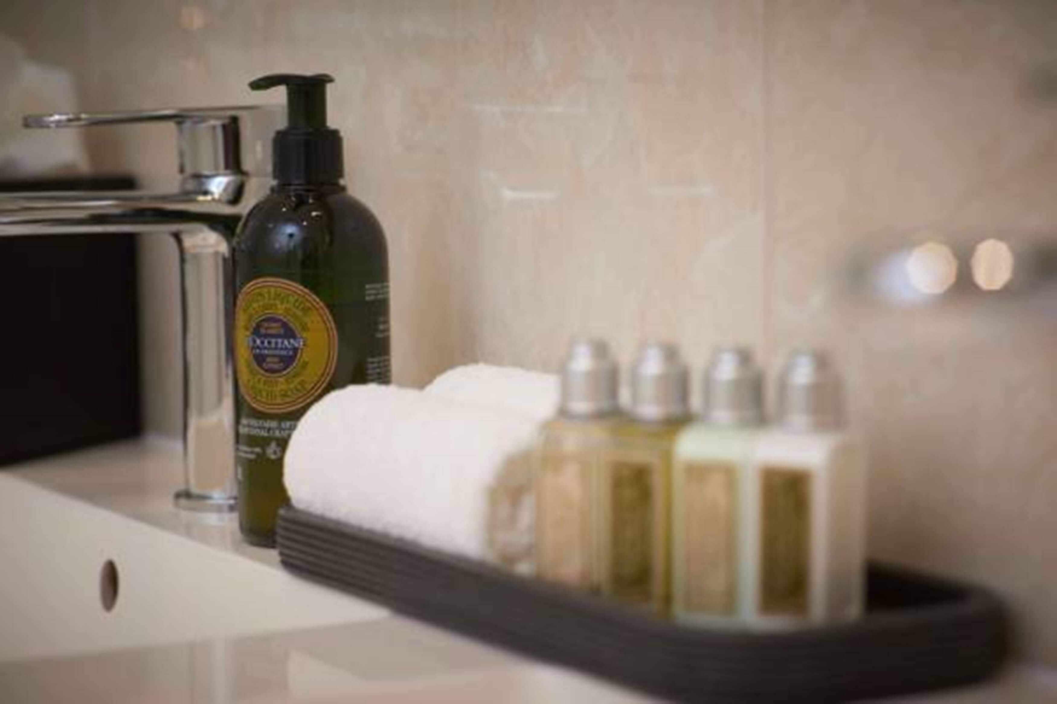 A bathroom with a bottle of Octane body wash, a towel, and a set of toiletries.