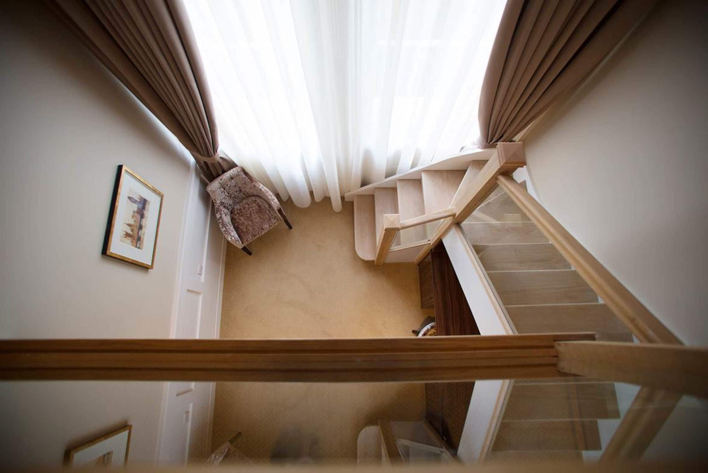 Un escalier avec une rampe en bois, une chaise et un tableau encadré au mur.