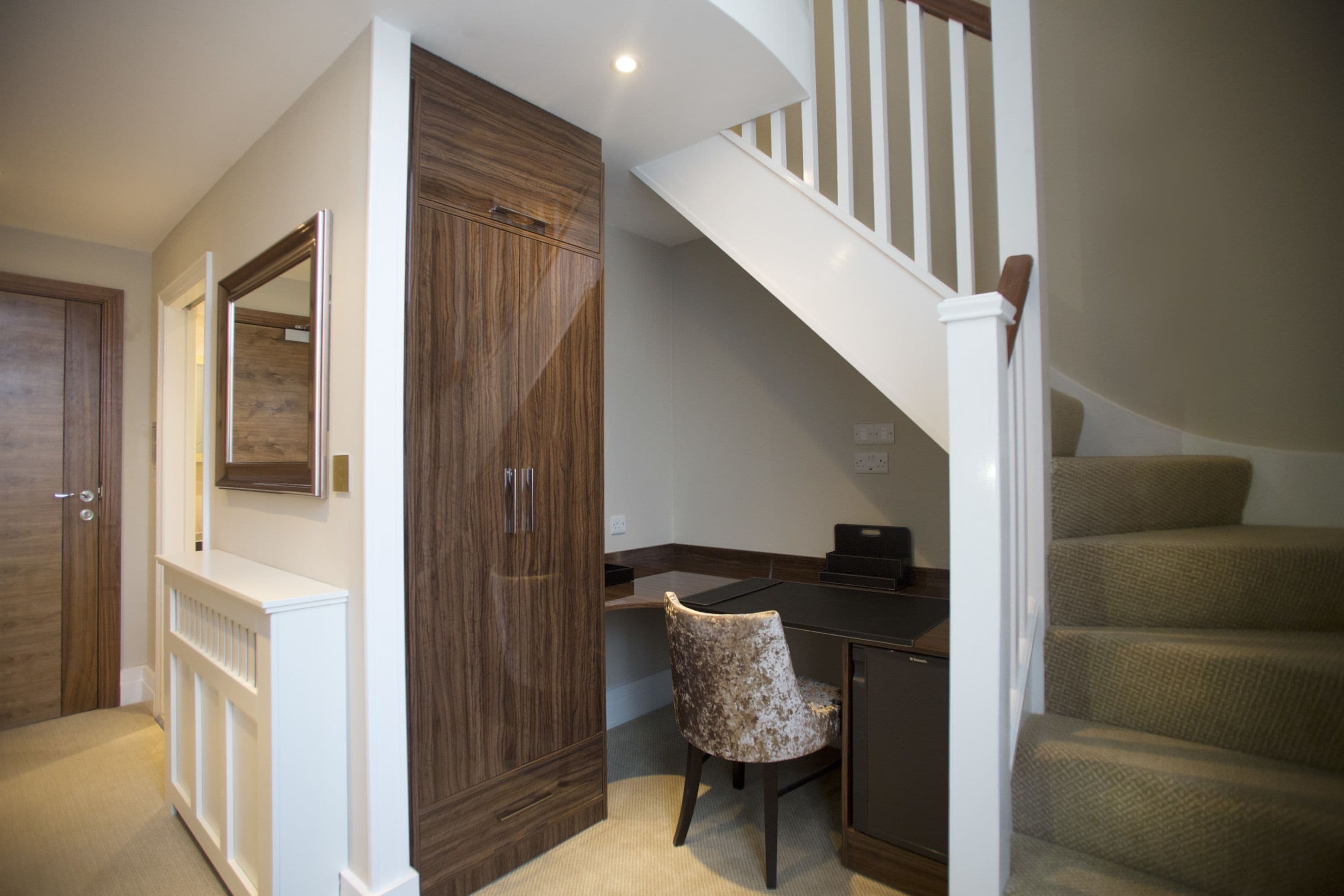 A home office with a desk, chair, and a staircase.