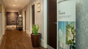 Ein Korridor mit dunklem Holzboden, einem Blumentopf, einem gerahmten Bild und einem Schild für The Lansbury Spa.