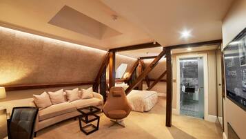 A modern loft bedroom with a sloped ceiling, a sofa, a chair, and a bed.