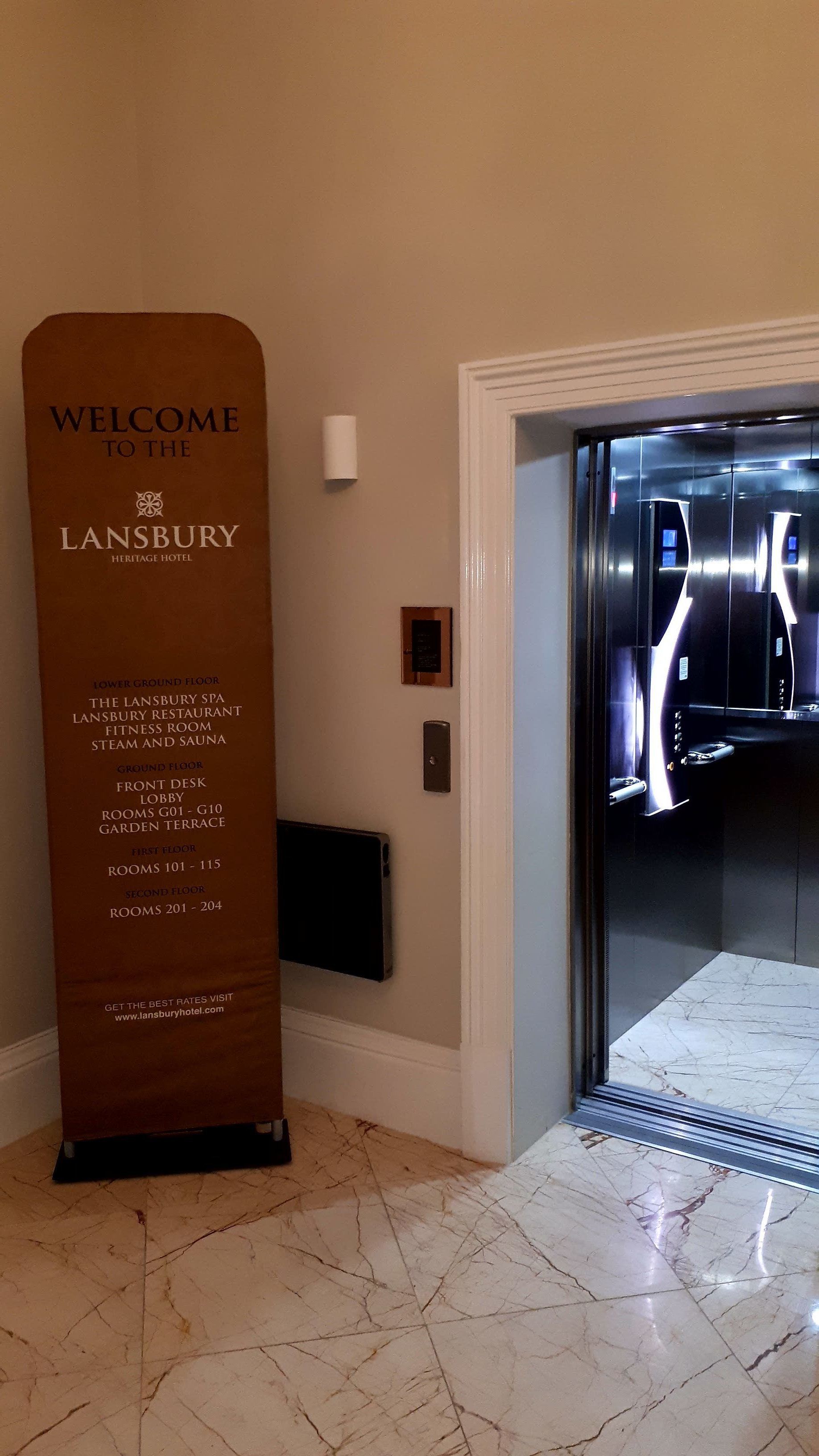 A welcome sign for Lansbury Heritage Hotel listing amenities and room numbers.
