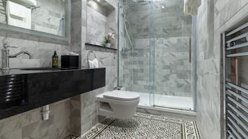 Ein modernes Badezimmer mit einer gläsernen Duschkabine, einem schwarzen Waschtisch und einer weißen Toilette, sowie Fliesen mit Muster.