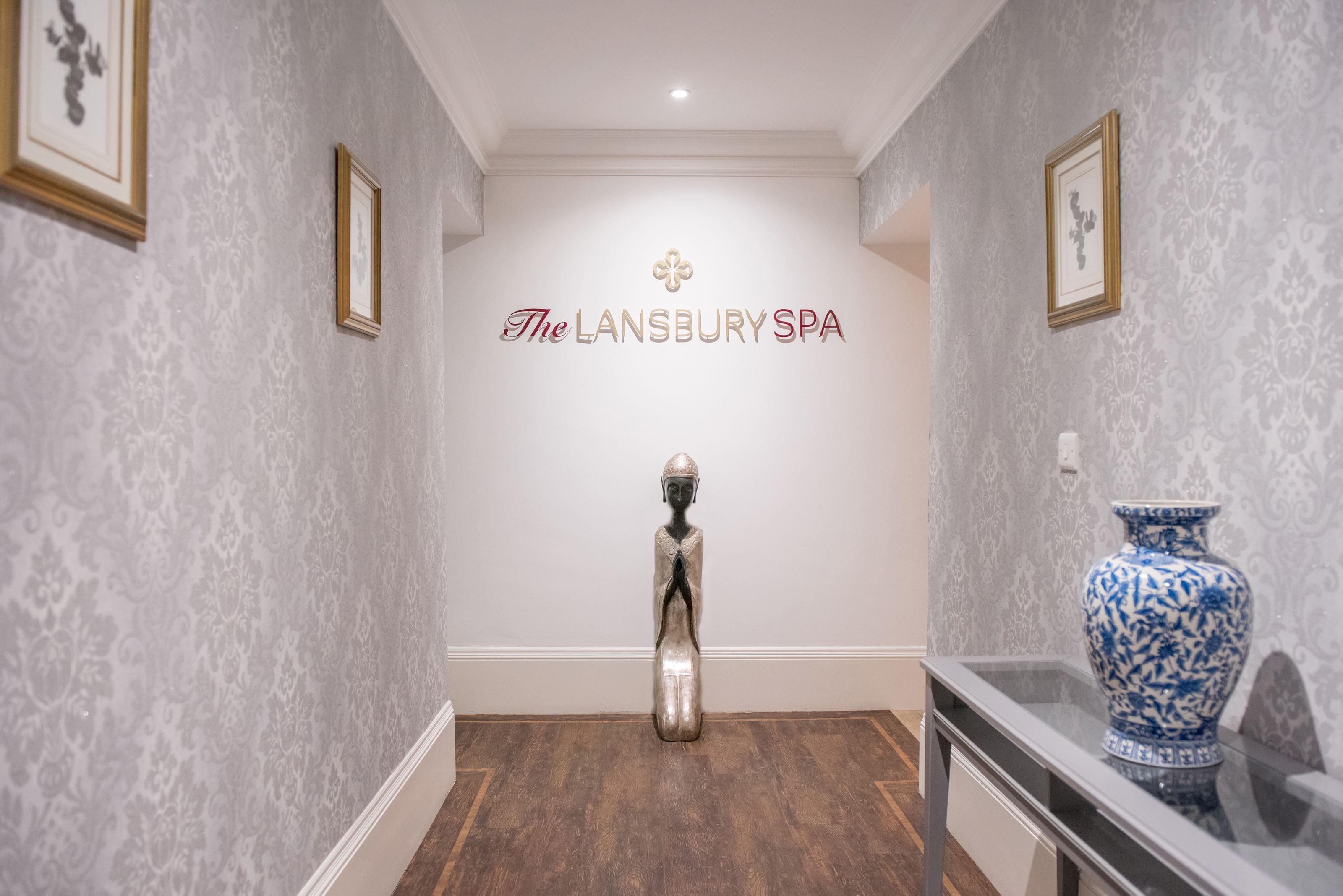 Un pasillo con un cartel que dice "The Lansbury Spa" y una estatua decorativa.