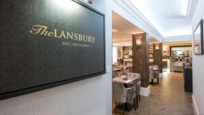 Ein modernes Interieur des The Lansbury Bar | Restaurant mit gemusterten Wandverkleidungen, Holzböden und einem gut beleuchteten Essbereich.