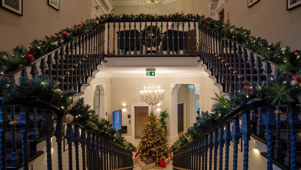 Eine prächtige Treppe mit einem Weihnachtsbaum in der Mitte, verziert mit Lichtern und Schmuck.