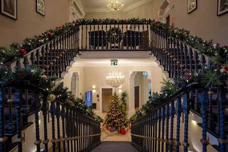 A grand staircase with a Christmas tree at the center, decorated with lights and ornaments.