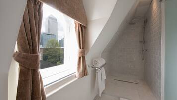 A modern bathroom with a skylight, a shower, and a towel rack.