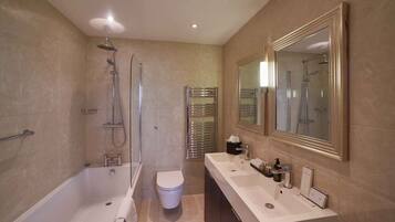 A modern bathroom with a bathtub, shower, toilet, and a large mirror.