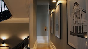 A hallway with framed architectural drawings on the wall, a wooden staircase, and a number '3' sign on the wall. - Porto Music Guest House (Porto)