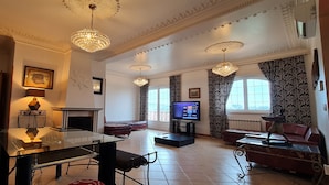 A spacious living room with a glass coffee table, a fireplace, a television, and a red sofa. - Silver Village Residence (Leiria)