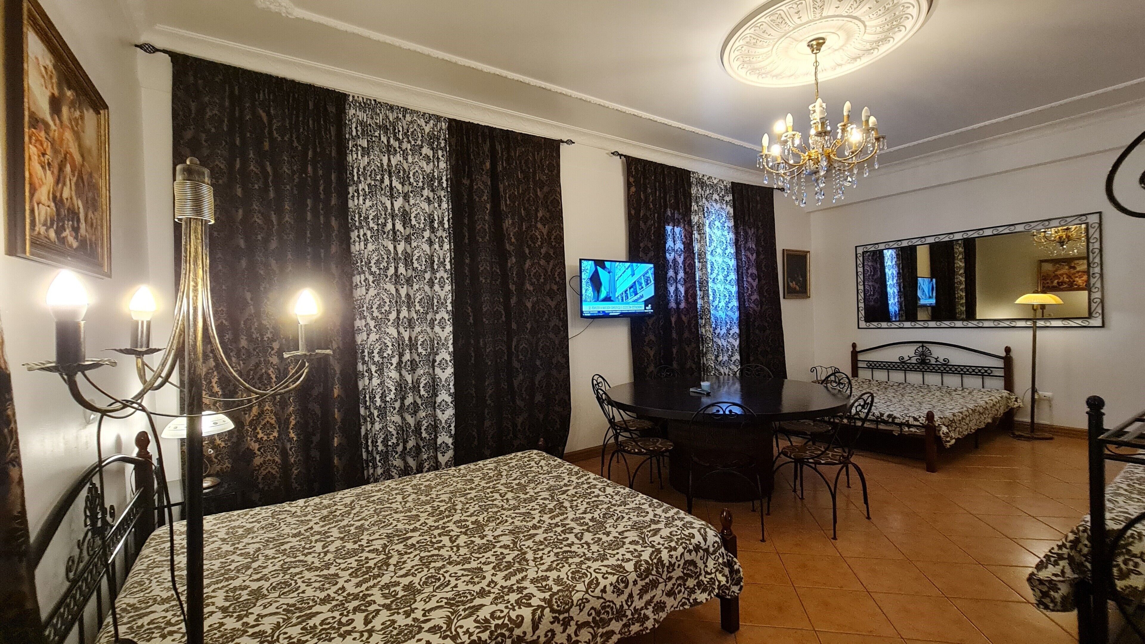 Una camera d'albergo con un letto, una scrivania, una sedia, una televisione e un lampadario.