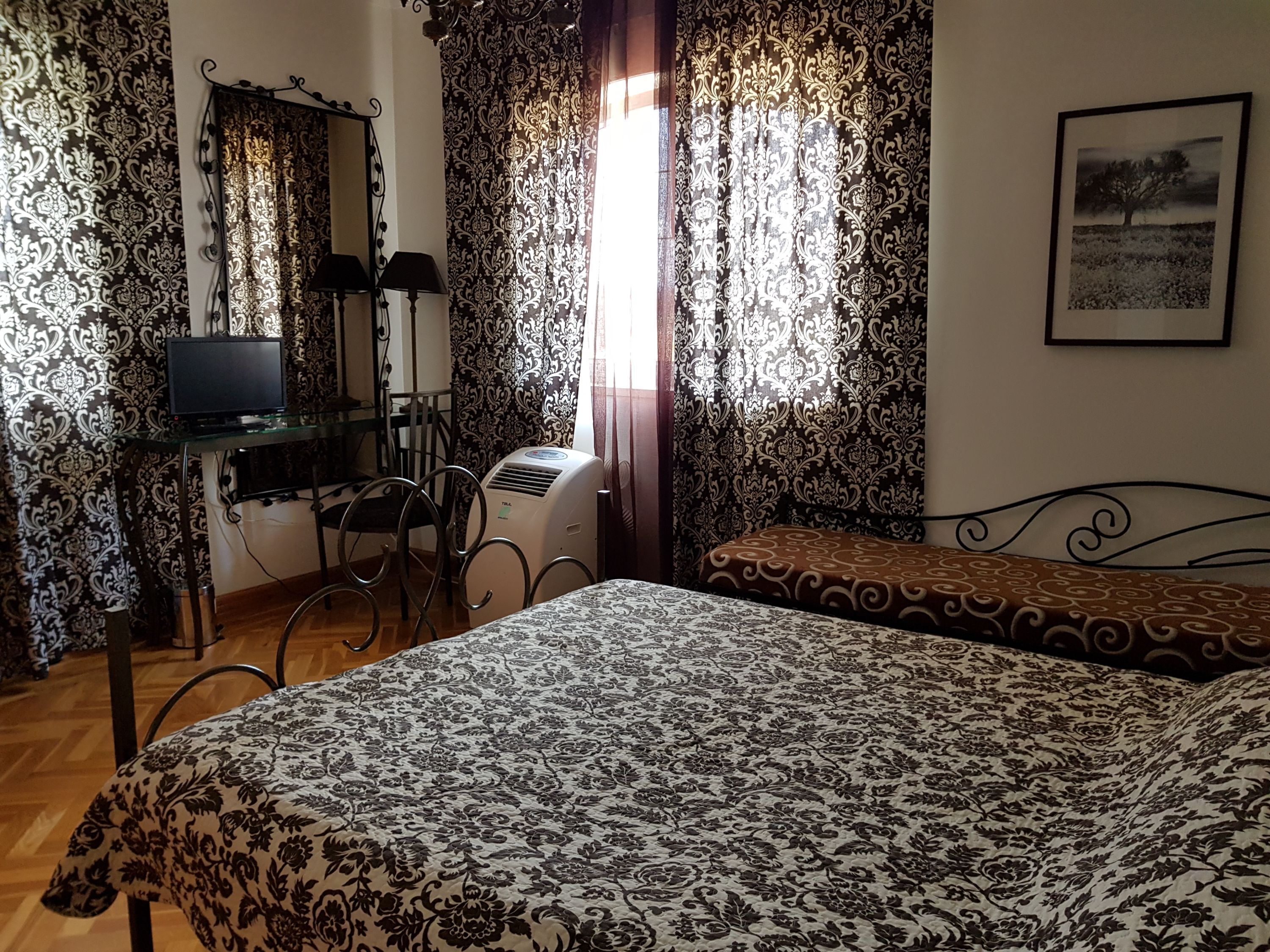 Une chambre avec un lit, un bureau avec un ordinateur et des rideaux à motifs floraux.