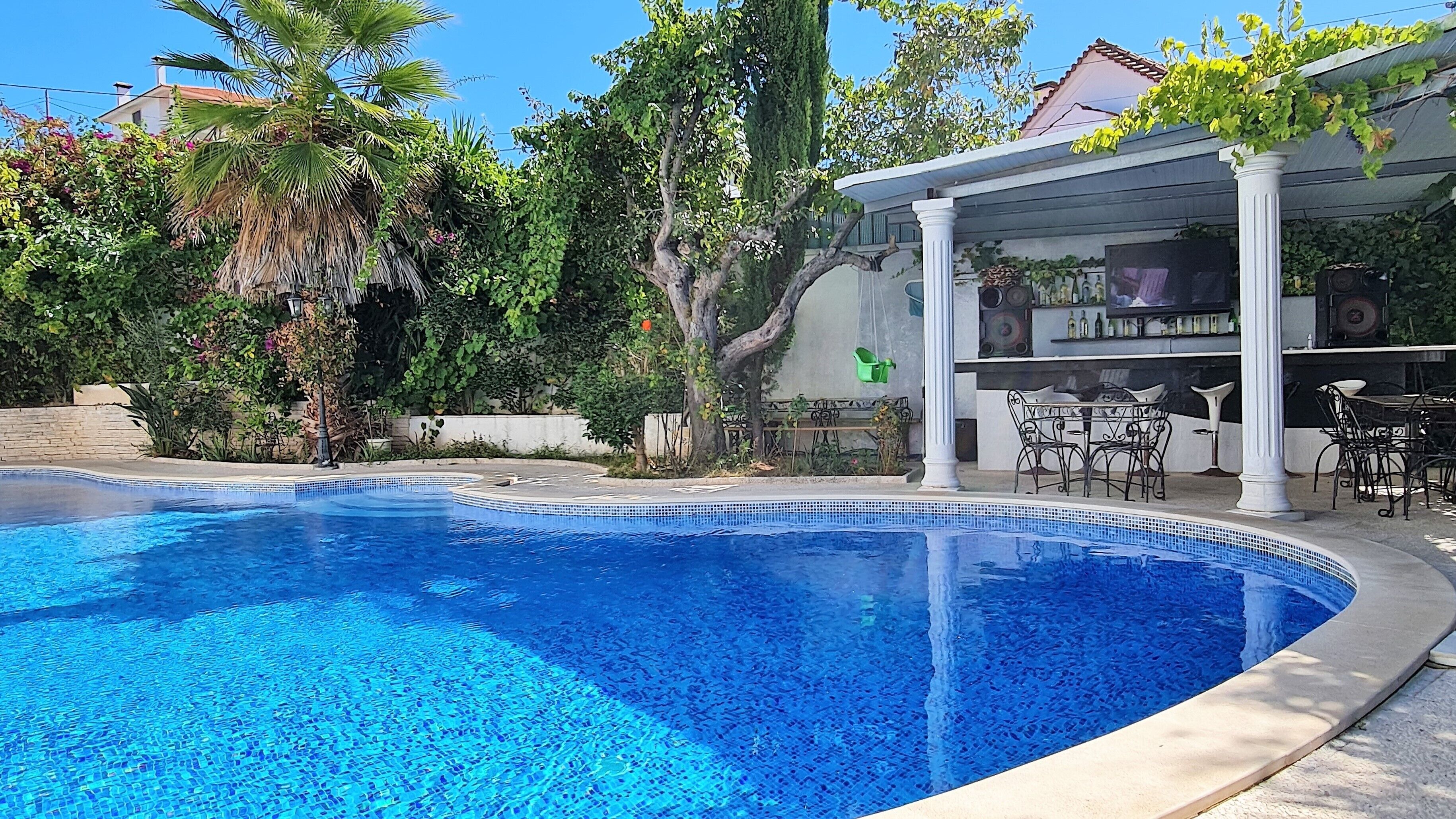 Une piscine dotée d’une pergola et d’un espace salon extérieur.