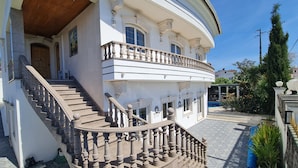 A two-story building with a curved balcony, a staircase with balusters, and a tiled courtyard. - Silver Village Residence (Leiria)
