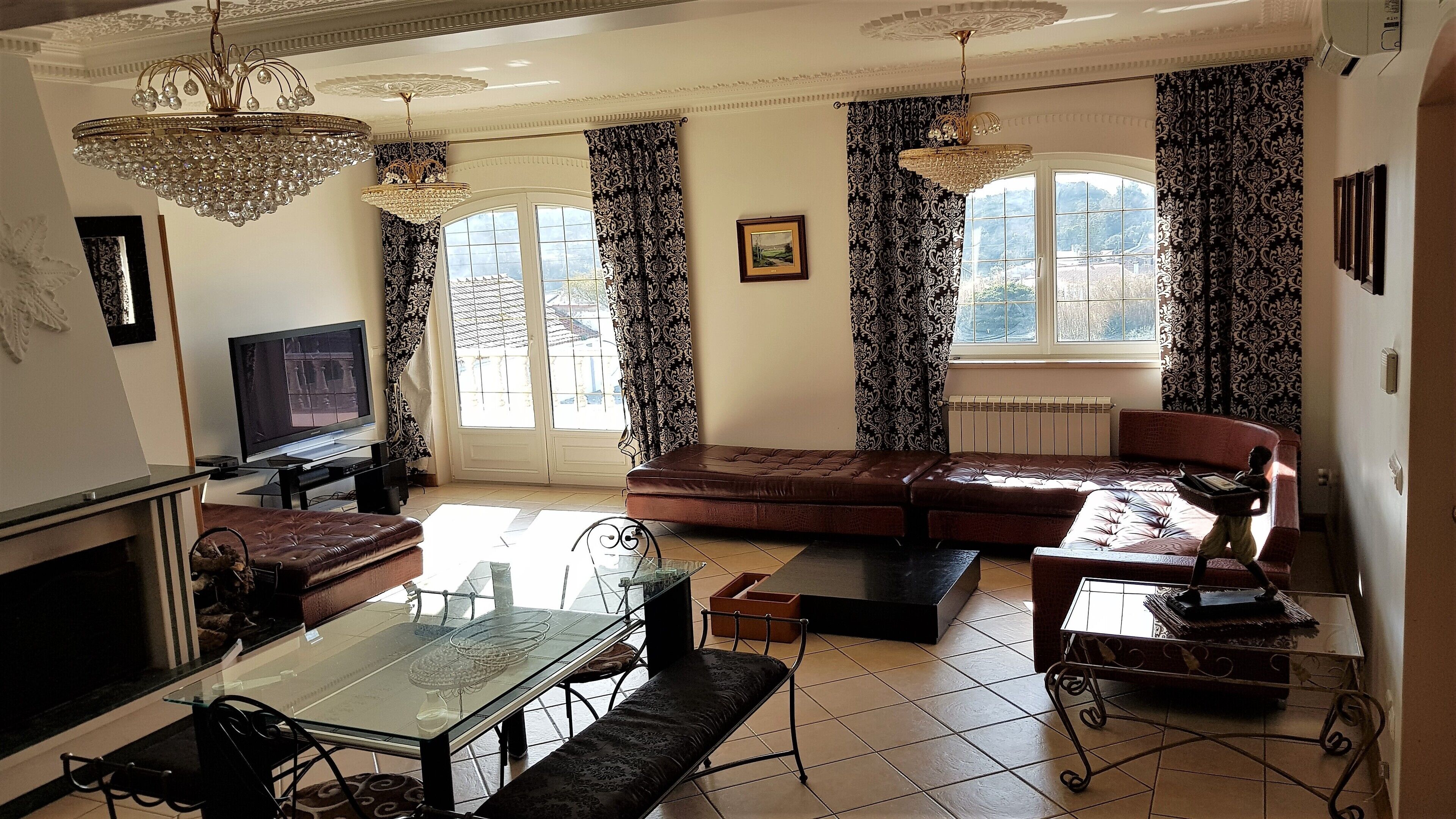 A spacious living room with a large sofa, a glass coffee table, and a television.