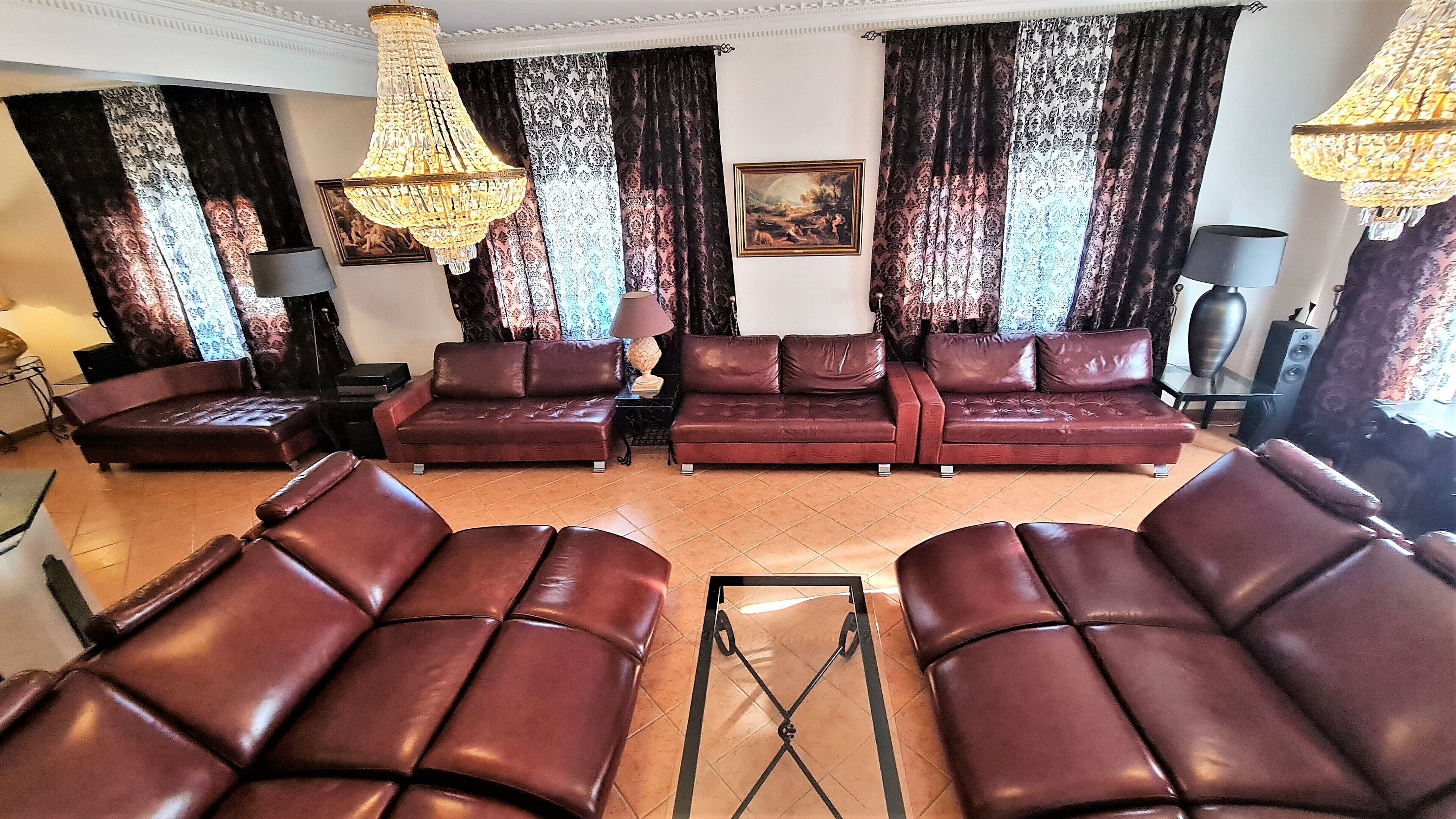 Uma sala de estar ampla com sofás de couro, uma mesa de centro e um candelabro.