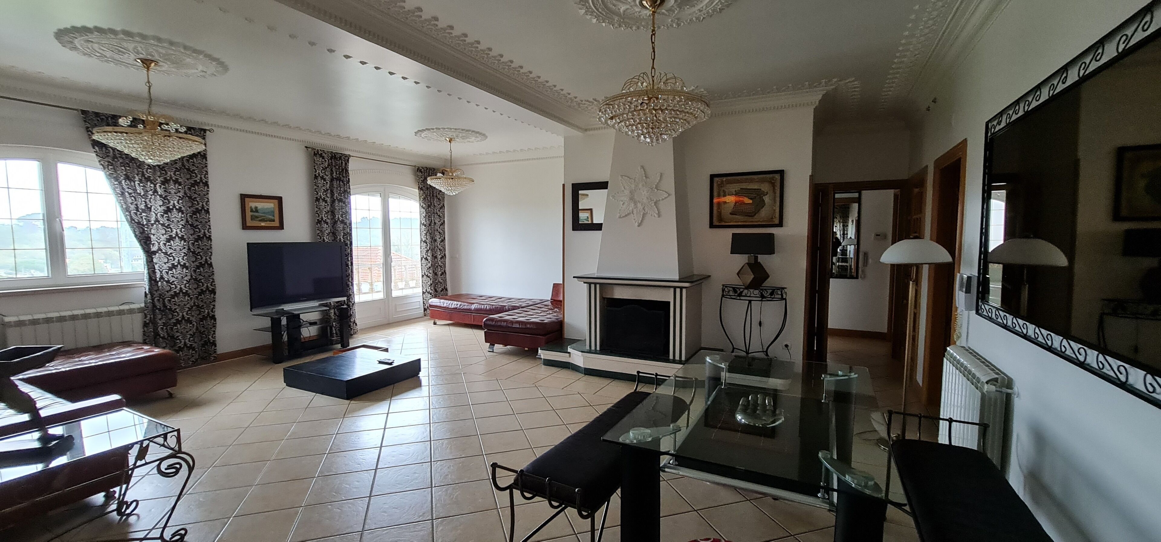 Un salón amplio con chimenea, televisor y zona de comedor con mesa de vidrio.