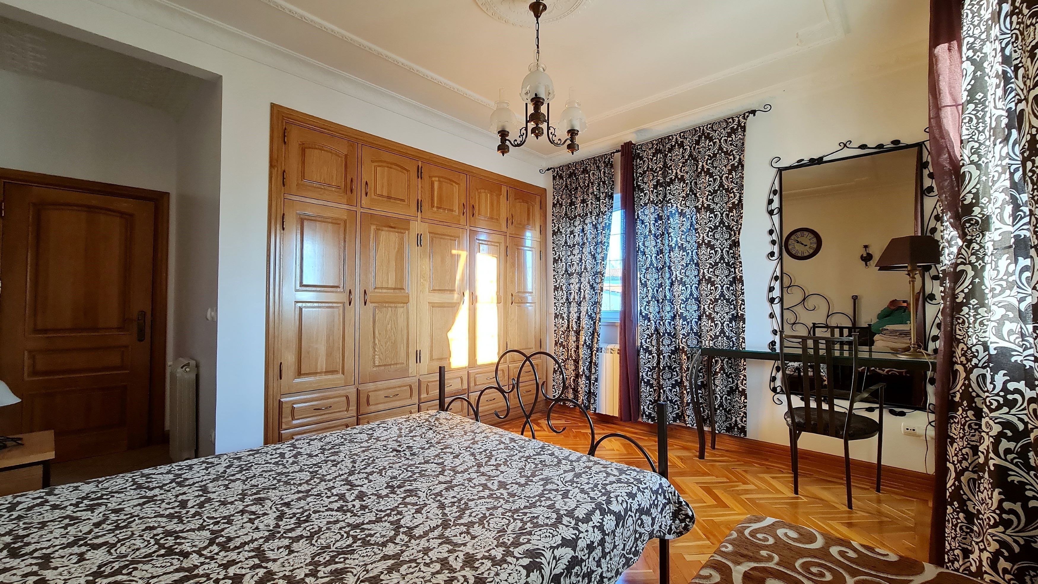 Ein Schlafzimmer mit einem großen Bett, einem Holzschrank und einem Essbereich mit Tisch und Stühlen.
