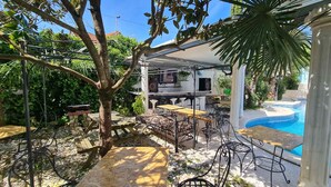 A covered outdoor area with a pool, tables, and chairs. - Silver Village Residence (Leiria)