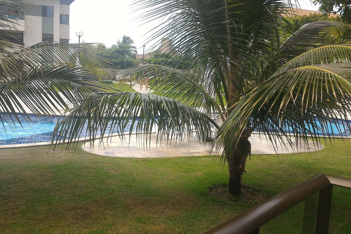 A pool area with palm trees and a building in the background.