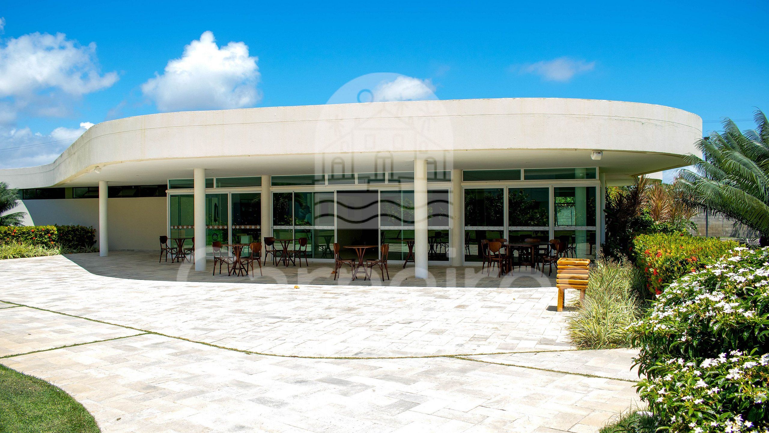 A modern building with a curved facade, large glass windows, and outdoor seating area.