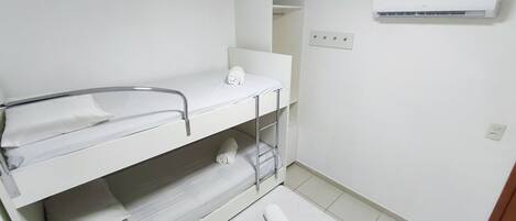 A small, clean room with a bunk bed, a sink, and an air conditioning unit.