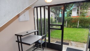 A small room with a desk and chair, a window with a view of a garden, and a door leading outside. - Hajdu Vendeghaz (Hajduszoboszlo)