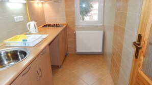 A compact kitchen with a gas stove, a sink, and a window providing natural light. - Hajdu Vendeghaz (Hajduszoboszlo)
