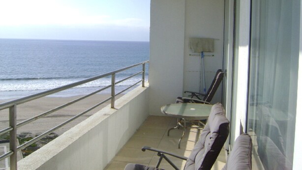 A balcony with a view of the ocean, a table with chairs, and a lamp. - Departamento Mar Serena 6 (La Serena)