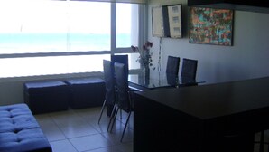 A modern office space with a large window, a glass table, and a bench. - Departamento Mar Serena 6 (La Serena)