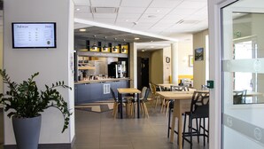 A modern restaurant with a menu board, seating area, and a counter with a coffee machine.