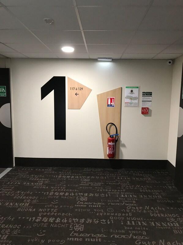Un pasillo con un letrero grande con el número 1, un extintor y señales de salida de emergencia.