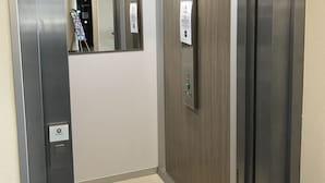 An elevator interior with a control panel, a mirror, and a wall-mounted sign.