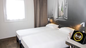 A hotel room with two beds, a window with curtains, a wall-mounted artwork, and a sign for B&B Hotels.