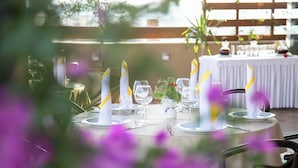 A table set with white plates, clear glasses, and candles with yellow ribbons. - Hotel Victoria (Tirana)
