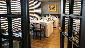 A dining area with tables set for multiple guests, featuring a wooden floor and a painting on the wall. - Hotel Victoria (Tirana)