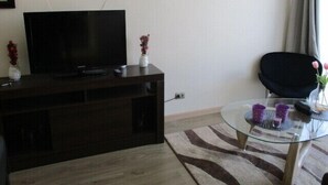 Familieleilighet, 3 soverom, balkong, bassengutsikt | Oppholdsområde | En 50-tommers Flatskjerm-TV med kabel-kanaler samt TV