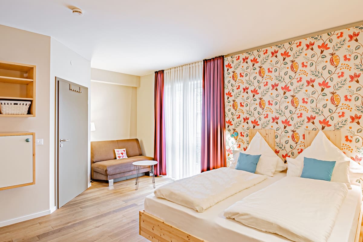 Une chambre à coucher avec un lit en bois, un canapé, une petite table et une armoire.