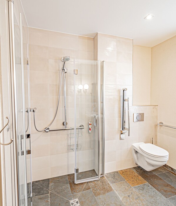 A modern bathroom with a glass-enclosed shower, a toilet, and a sink.