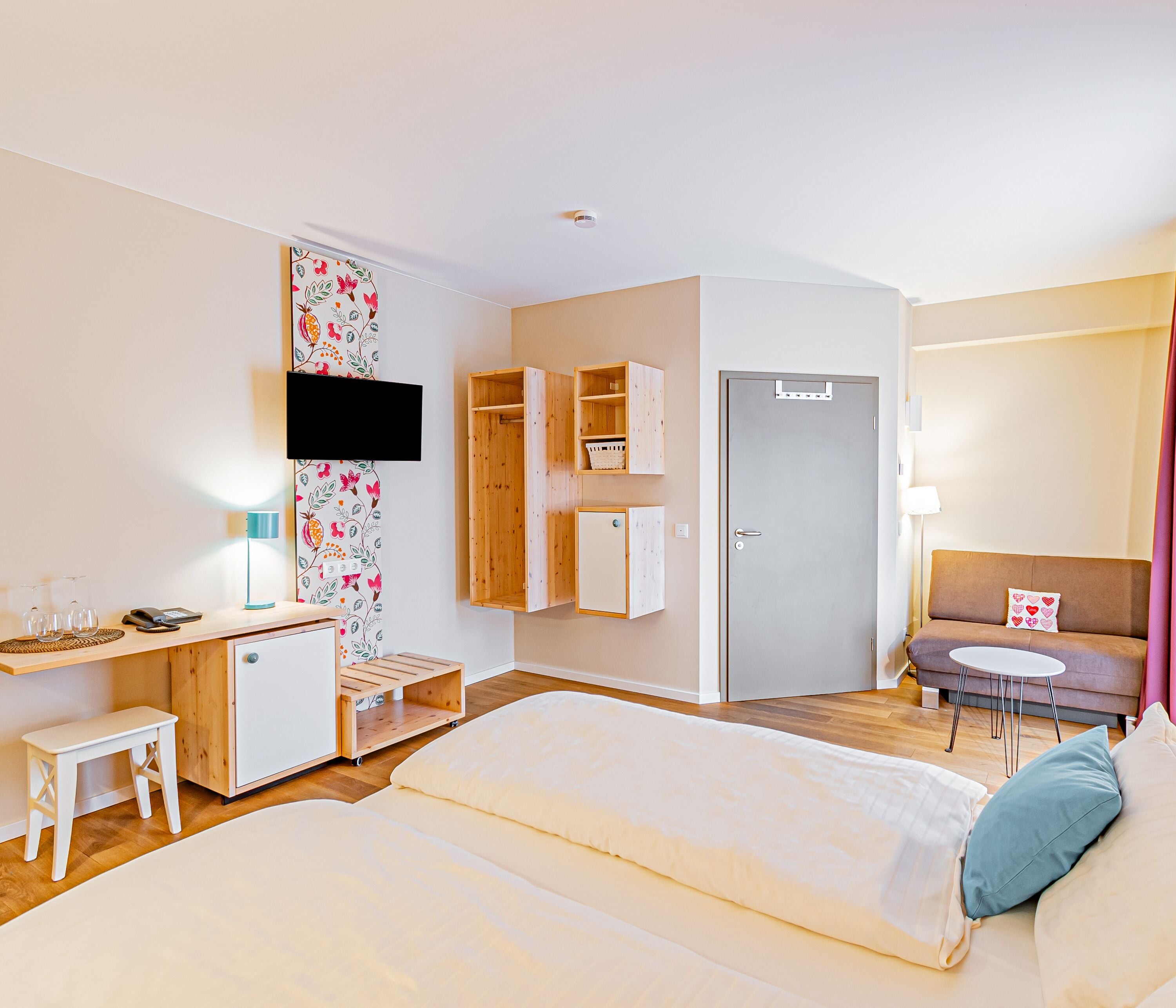 Ein Schlafzimmer mit Bett, Schreibtisch, Stuhl, Kleiderschrank, Fernseher und einem kleinen Tisch.