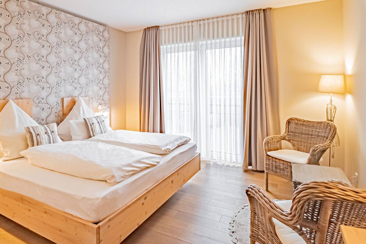 Une chambre d’hôtel avec un grand lit, une chaise en osier et une lampe.