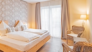 Una habitación de hotel con una cama grande, una silla de mimbre y una lámpara.
